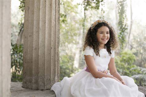 Enfant en tenue de communion dans jardin lumineux